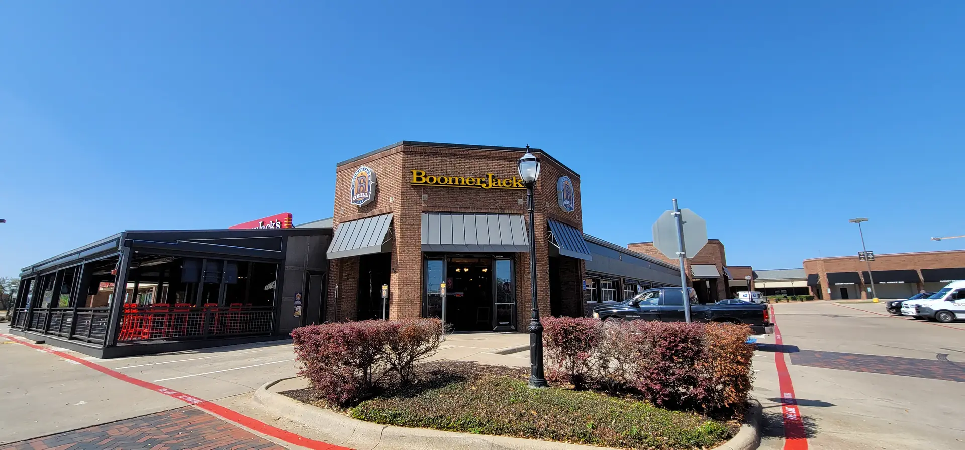 BoomerJack's restaurant exterior with patio seating, parking lot, and clear blue sky