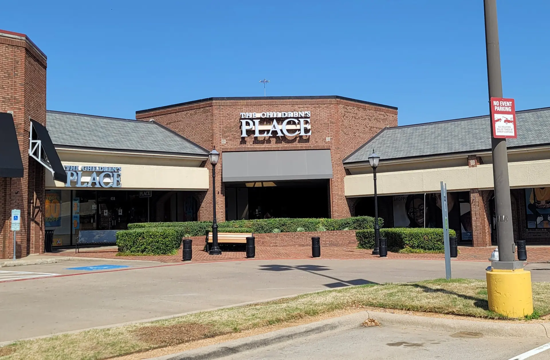The Children's Place storefront in brick retail center with empty walkway and parking area