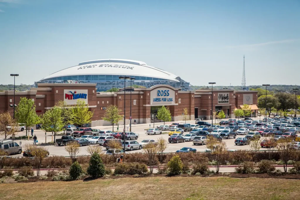 Shopping center with PetSmart, Ross, and Michaels in front of AT&T Stadium and full parking lot