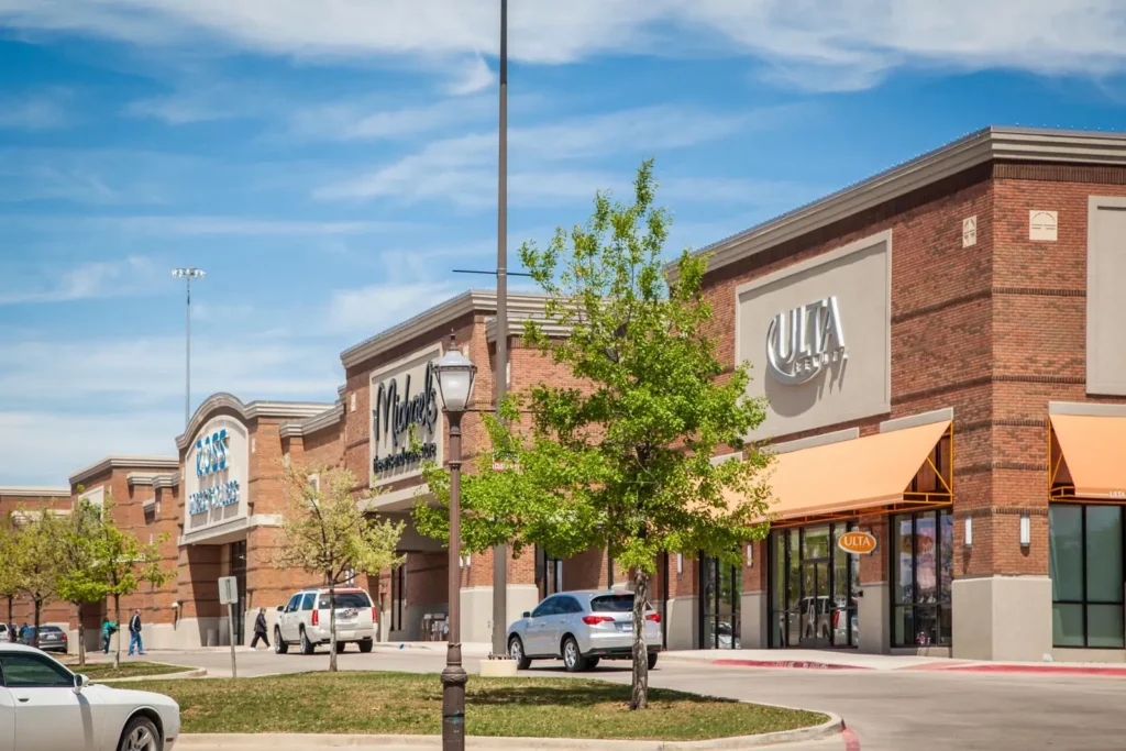 Retail strip with Ulta, Michaels, and Ross storefronts, parked cars, and sidewalk trees