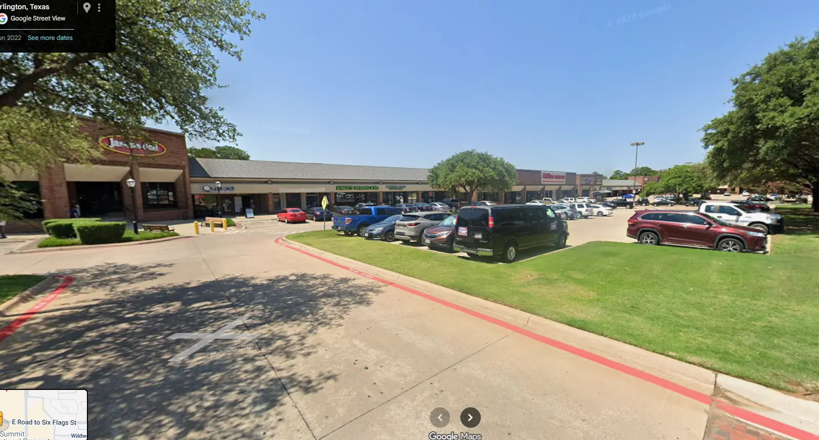 Wide-angle Google Street View of a suburban strip mall in Texas with a brick facade, featuring "Jason's Deli," green grass medians, and a parking lot full of cars under a bright, clear sky.